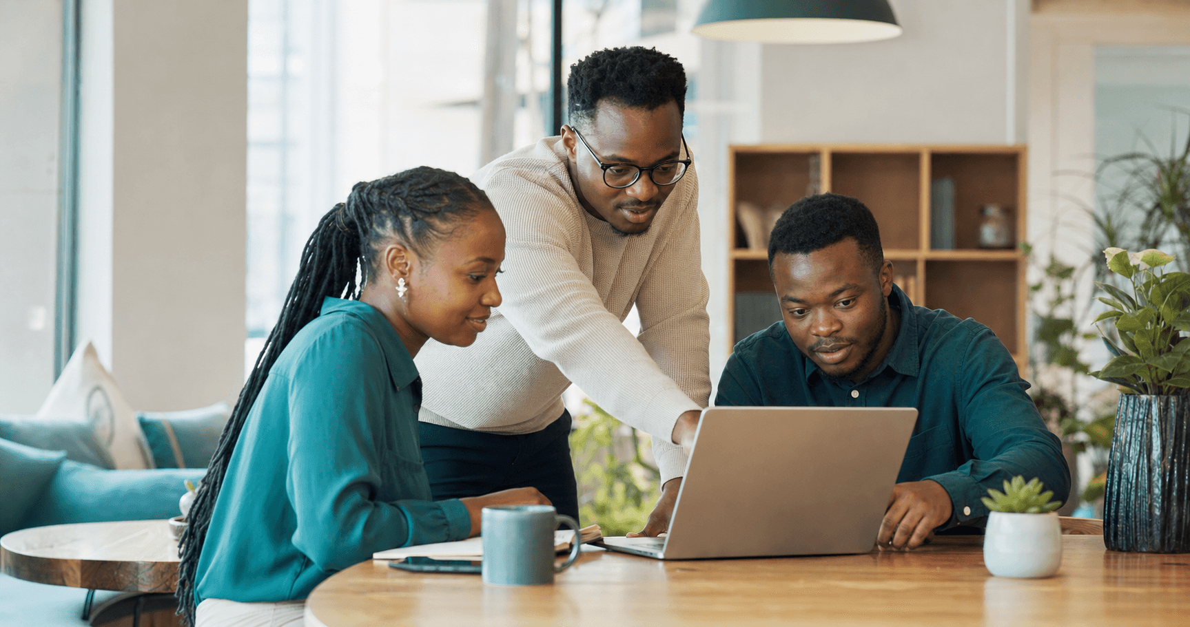 Business owners and a software specialist working together around a laptop